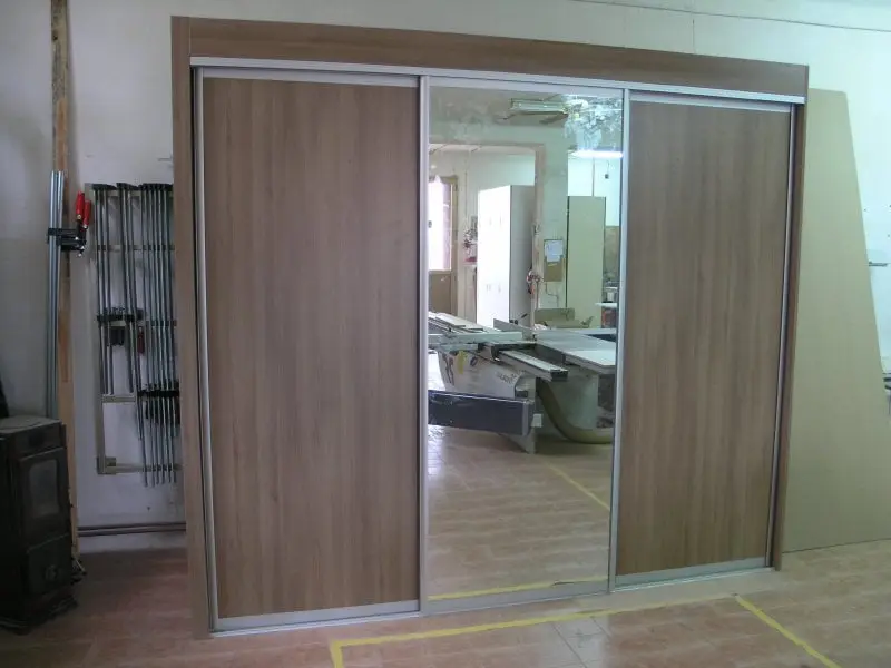 Ormar s kliznim vratima u radionici; u ogledalu se vidi formatna pila