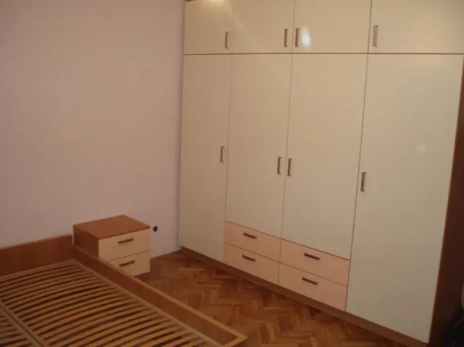 Ormar u krem boji s ladicama i noćni ormarić u spavaćoj sobi