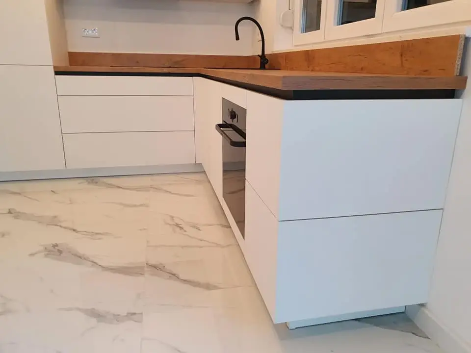 Detalj bijele kuhinje s drvenom radnom pločom i ugradbenom pećnicom